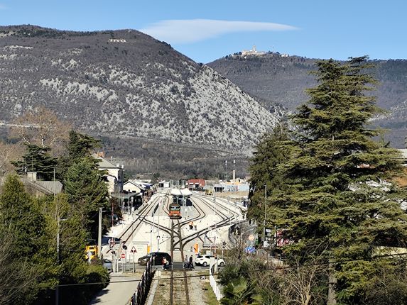 Železniški tiri s postajo, v ozadju Sabotin in Sveta gora. Foto: Blaž Kosovel.  