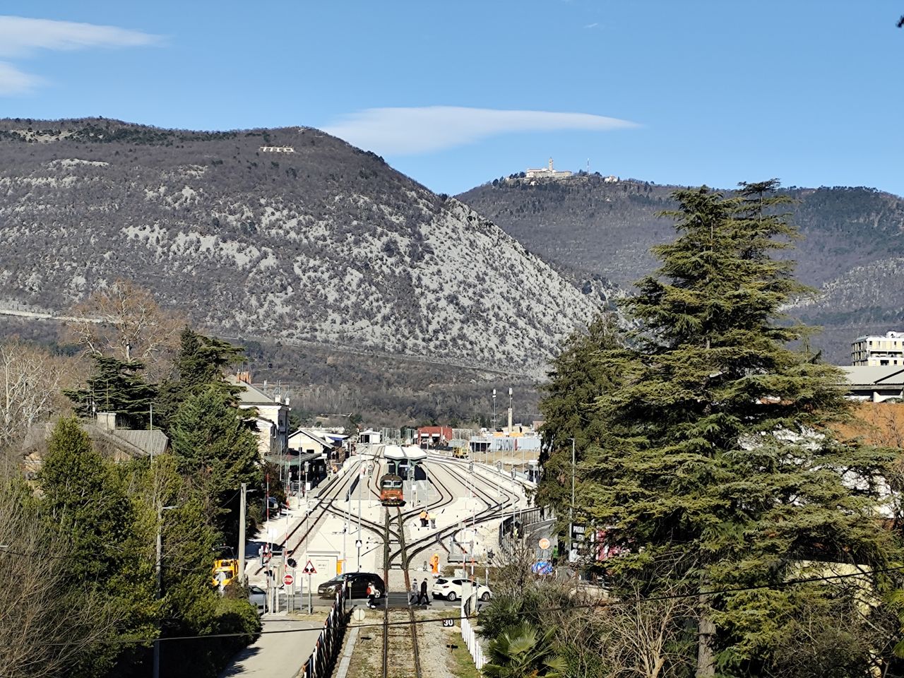 Železniški tiri s postajo, v ozadju Sabotin in Sveta gora. Foto: Blaž Kosovel.  